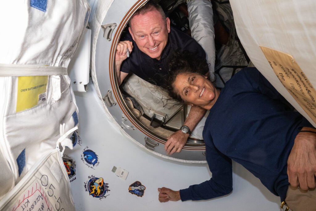 NASA astronauts Butch Wilmore and Suni Williams smile as they float inside the vestibule between the forward port on the International Space Station's Harmony module and the Starliner spacecraft.