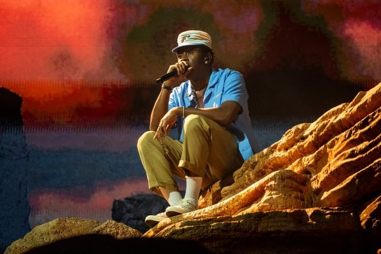 A man is sitting on a stage holding a microphone.